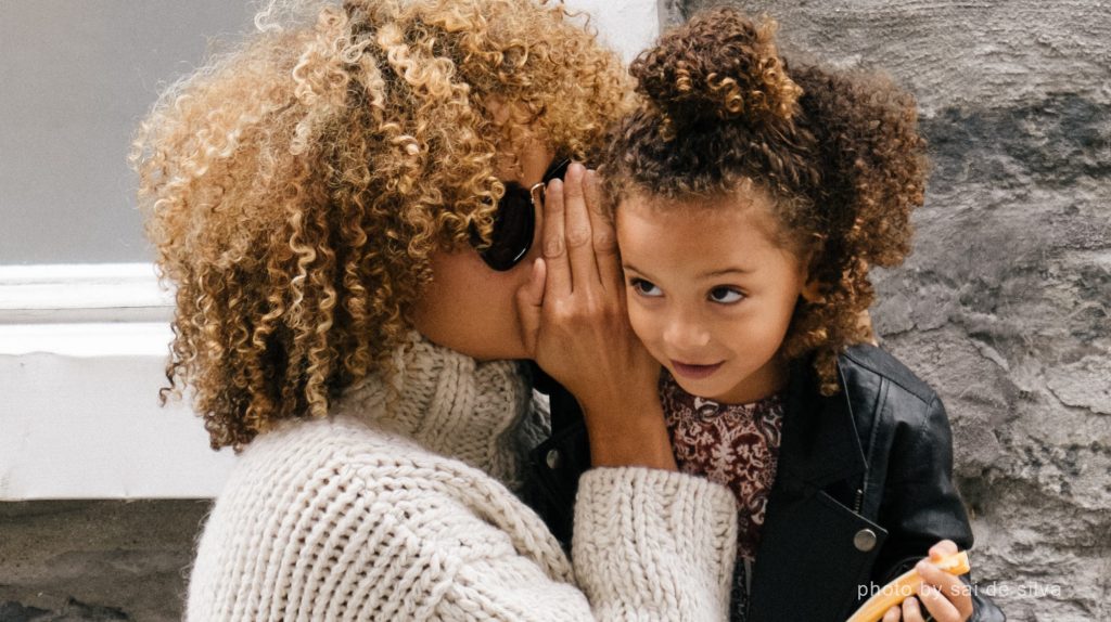 mother whispering in child's ear