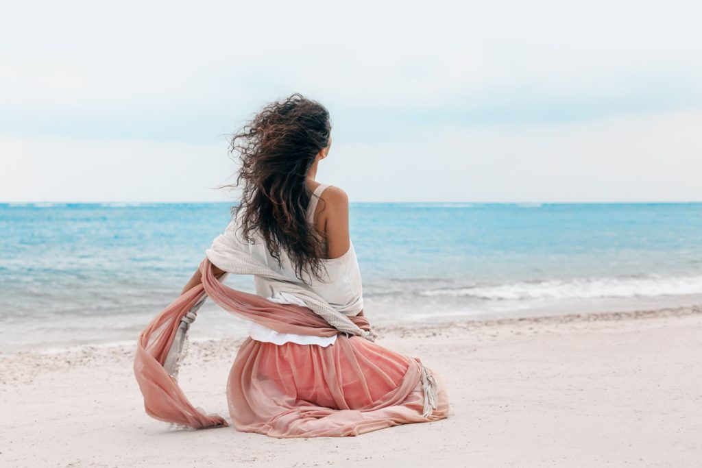 Women sitting on peaceful beach enjoying her solitude as she practices affirmations after narcissistic abuse (image by Timothy Dykes)